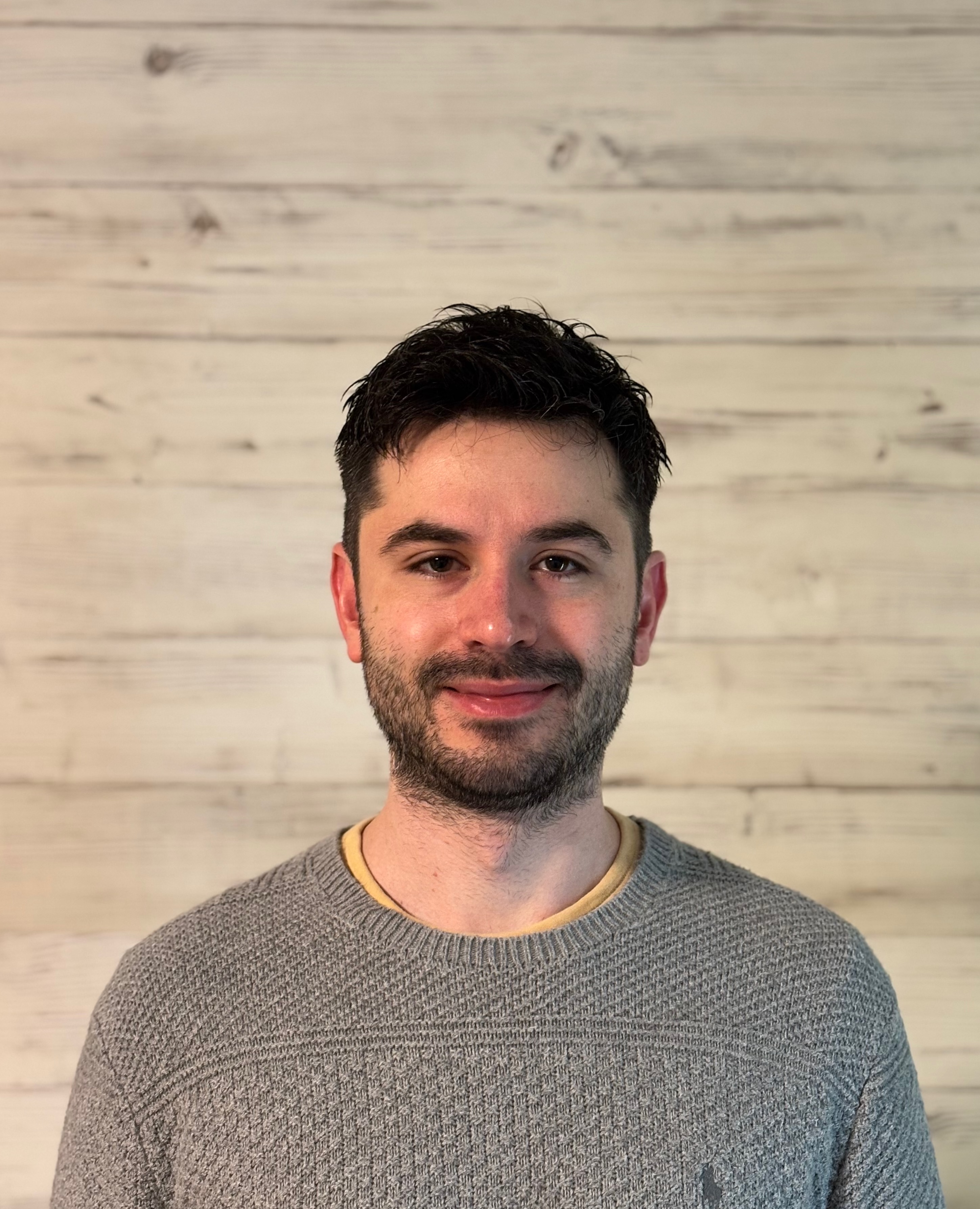 Aybars smiling in a gray sweater.